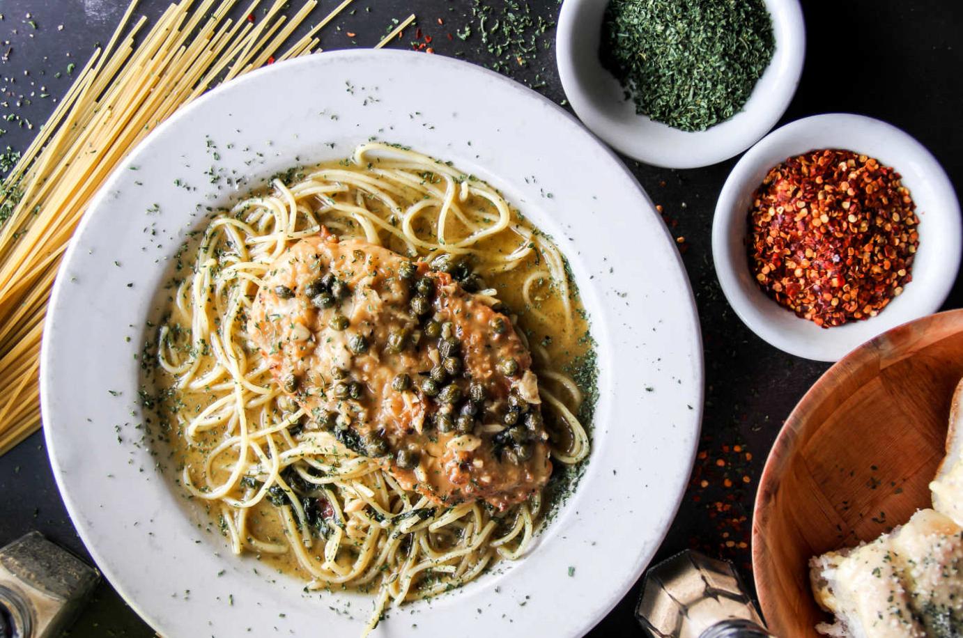 Chicken piccata over spaghetti with chili flakes and herbs