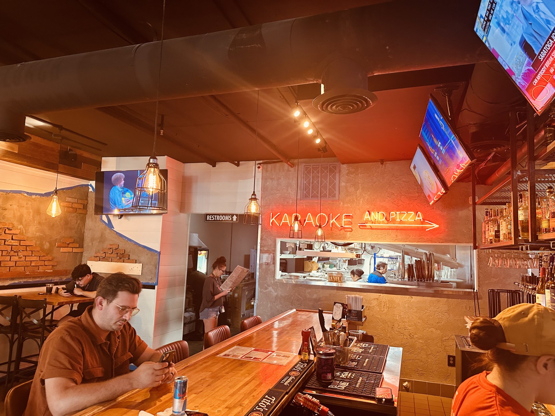 The bar at Marietta Square under a red karaoke sign, with guests seated along the counter